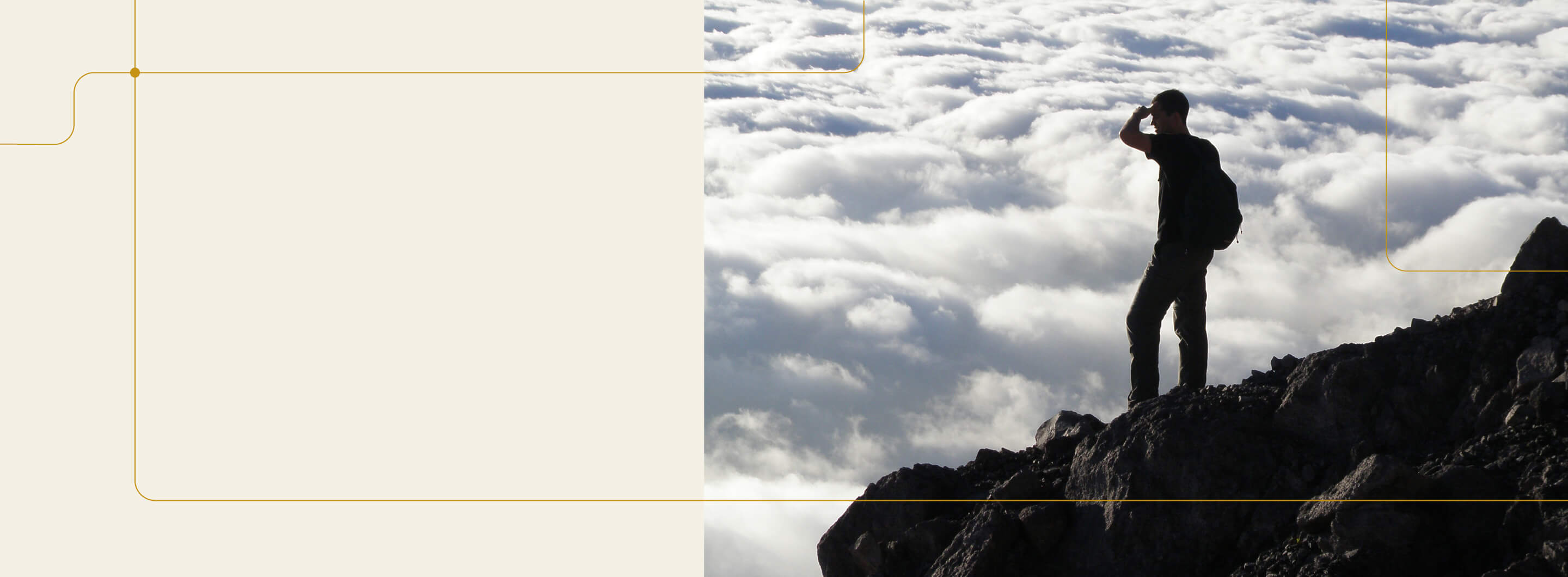 Man standing at the top of a mountain looking over a horizon of clouds